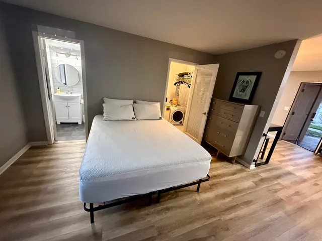 a bed sitting in a bedroom next to a window with wooden floor