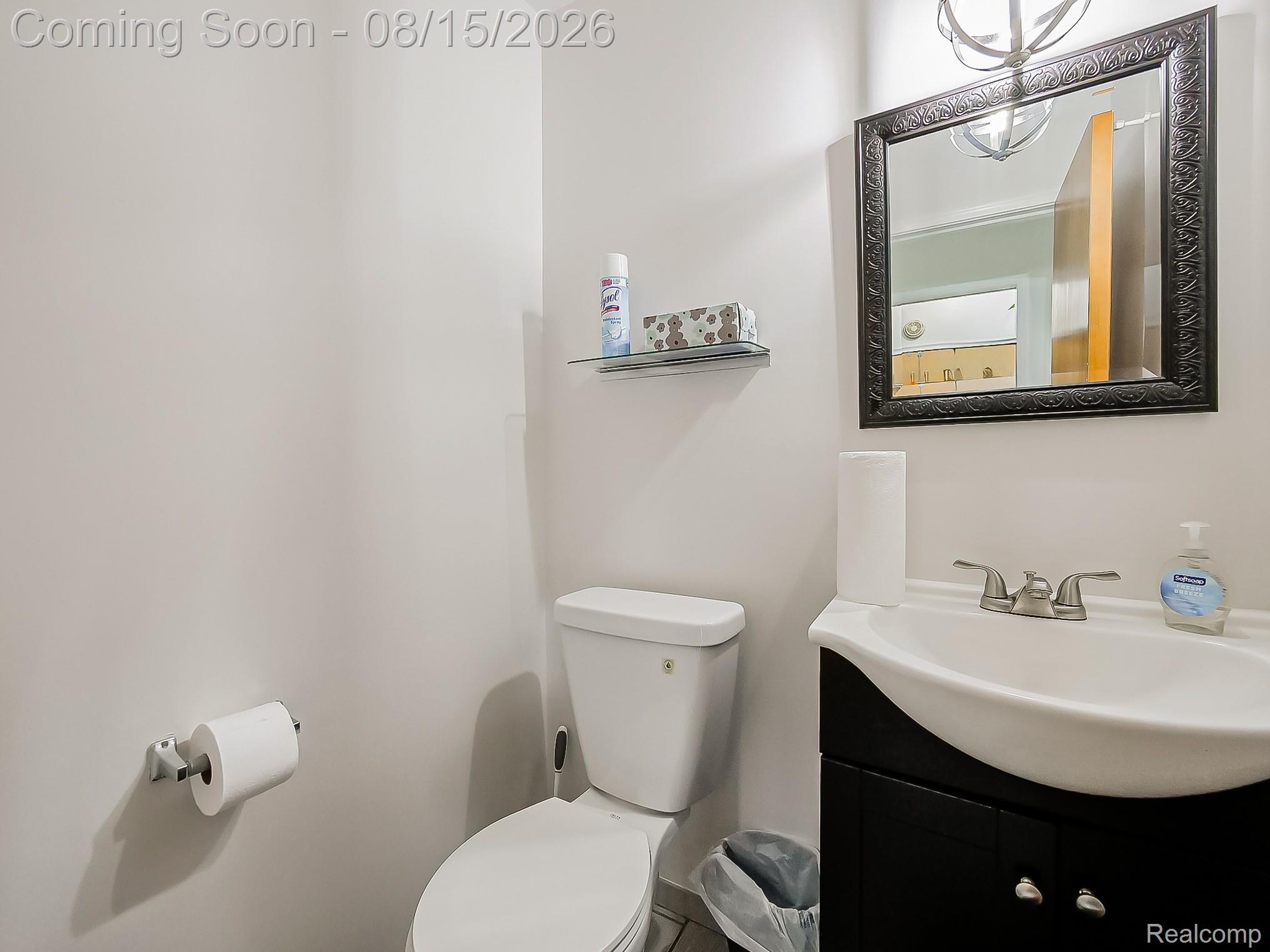 21131 Harvard Road Southfield, MI 48076 - Photo 10 of 33 White vanity sink with brushed nickel faucet, black framed mirror, and a glass wall shelf