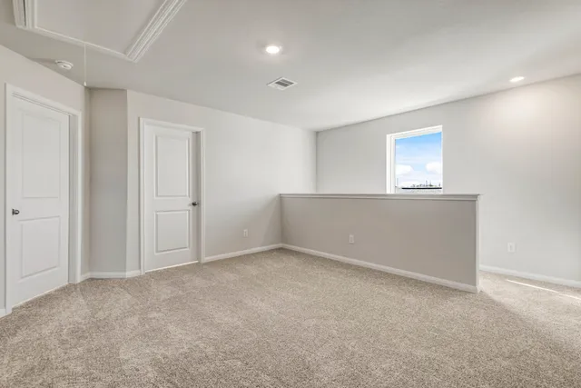 a view of an empty room with wooden floor and a ceiling fan