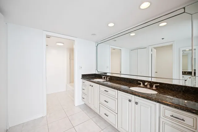 a spacious bathroom with a granite countertop double vanity and mirror