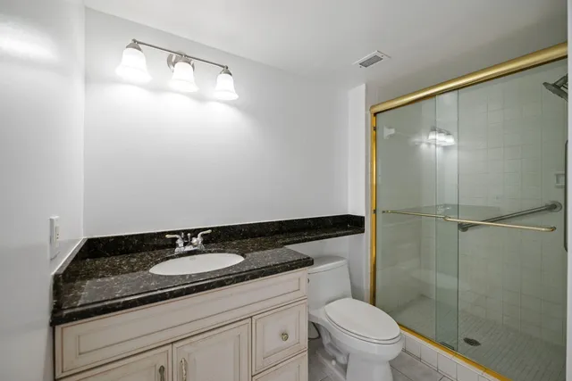 a bathroom with a granite countertop sink toilet and shower