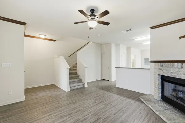 a view of an empty room with wooden floor and a fireplace