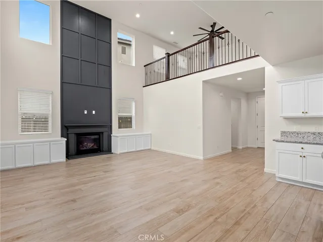 a view of empty room with wooden floor and kitchen