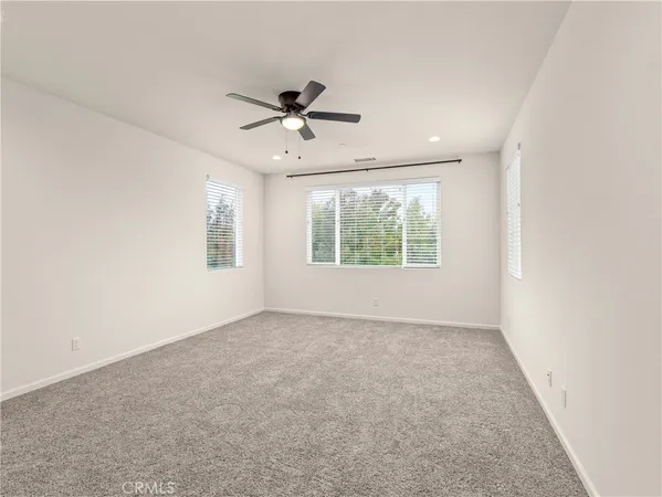 an empty room with windows and fan
