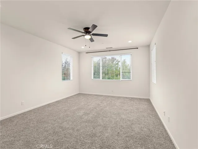 an empty room with windows and fan