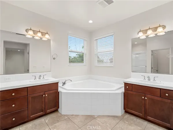 a spacious bathroom with a tub double sink large mirror and window