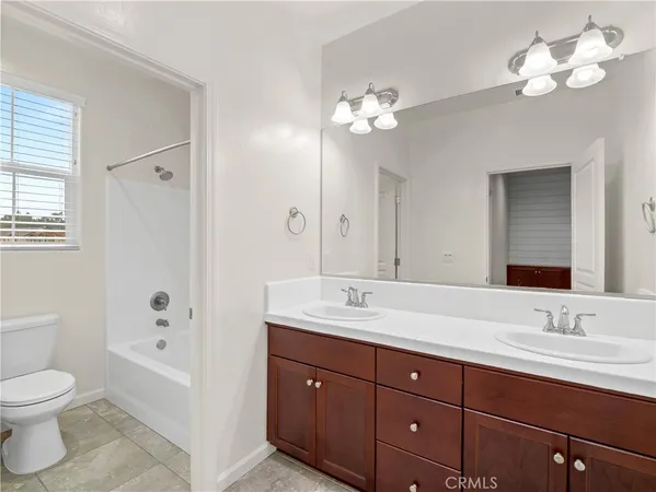 a spacious bathroom with a granite countertop sink a toilet a mirror and shower