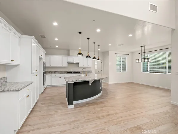 a large kitchen with stainless steel appliances kitchen island granite countertop a large counter top and a sink