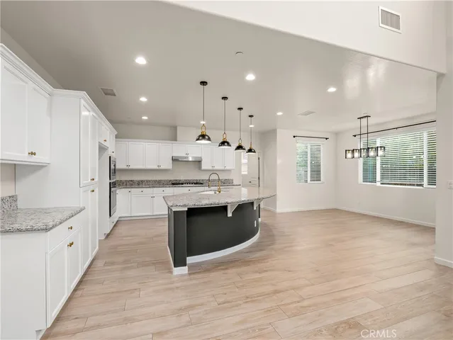 a large kitchen with stainless steel appliances kitchen island granite countertop a large counter top and a sink
