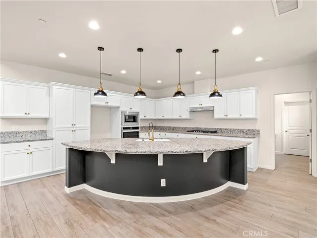 a view of kitchen with stainless steel appliances granite countertop sink stove and wooden floor