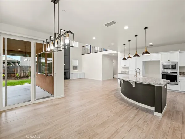 a large kitchen with stainless steel appliances kitchen island granite countertop a refrigerator a stove a sink and a wooden floors