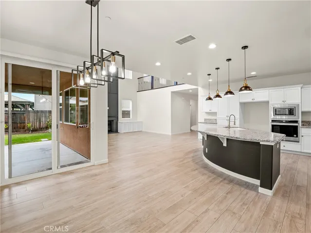 a large kitchen with stainless steel appliances kitchen island granite countertop a refrigerator a stove a sink and a wooden floors