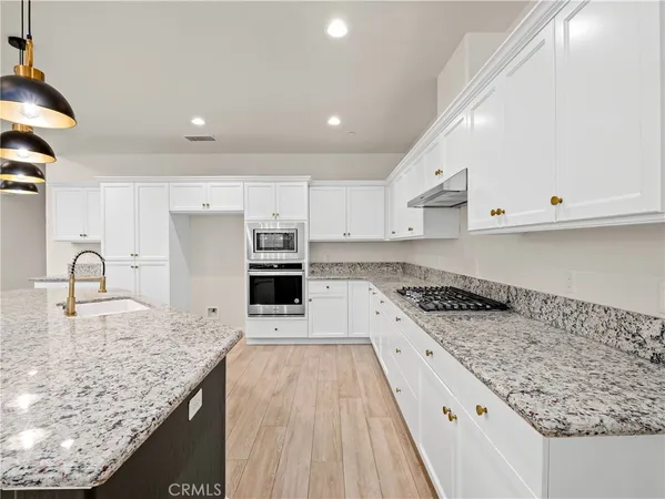 a kitchen with stainless steel appliances granite countertop a sink stove and cabinets