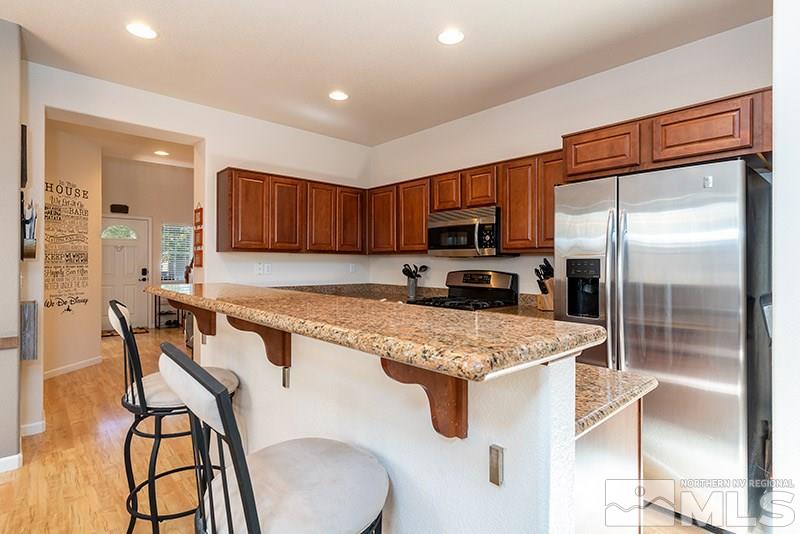 515 Connemaras Court Reno, NV 89521 - Photo 5 of 14 a kitchen with stainless steel appliances granite countertop a refrigerator a stove a sink a dining table and chairs with wooden floor