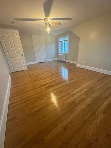 a view of empty room with window and wooden floor