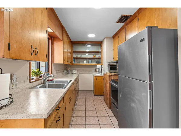 a kitchen with stainless steel appliances granite countertop a sink a stove a refrigerator a washer dryer and a refrigerator