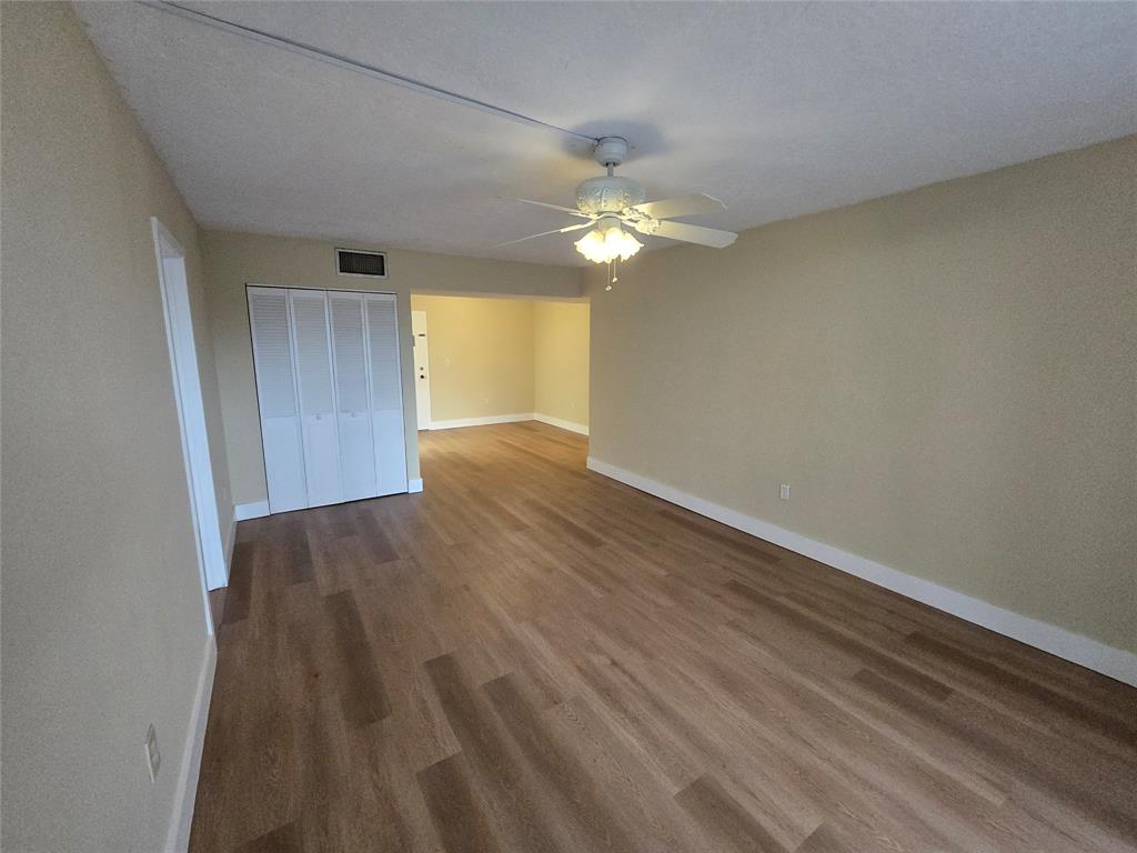 1681 Northwest 70th Avenue, Unit 403 Plantation, FL 33313 - Photo 20 of 54 an empty room with wooden floor chandelier fan and windows