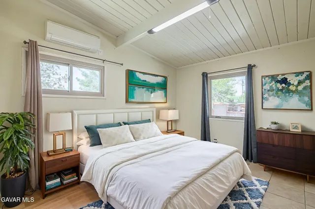 a bedroom with a bed and a potted plant next to a window