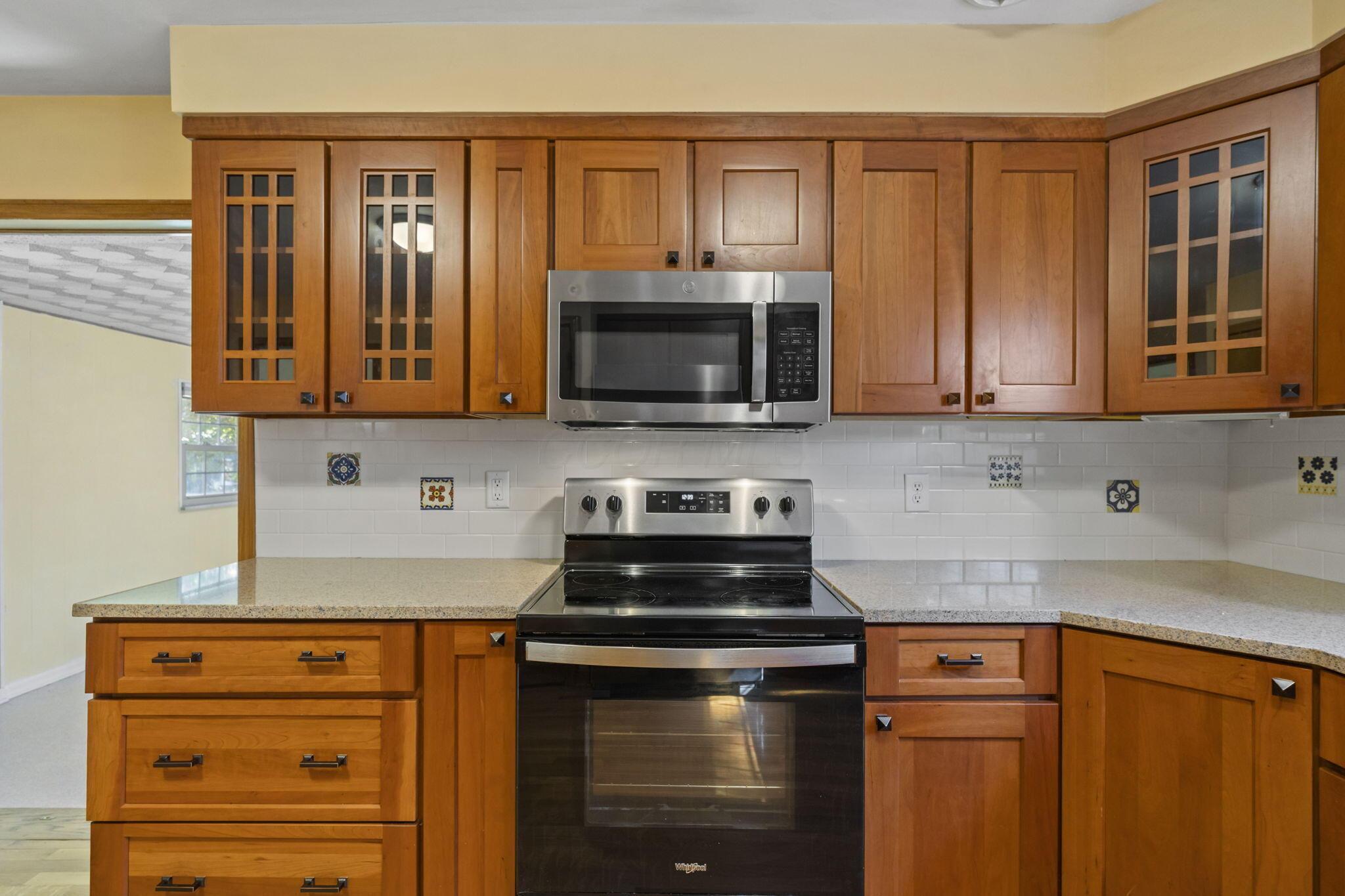 40 South Kellner Road Columbus, OH 43209 - Photo 7 of 57 Warm wood cabinetry with glass-front upper cabinets and bronze hardware frames this updated kitchen featuring stainless steel appliances, including a gas range and over-the-range microwave