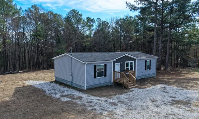 a view of a house with a yard in the forest