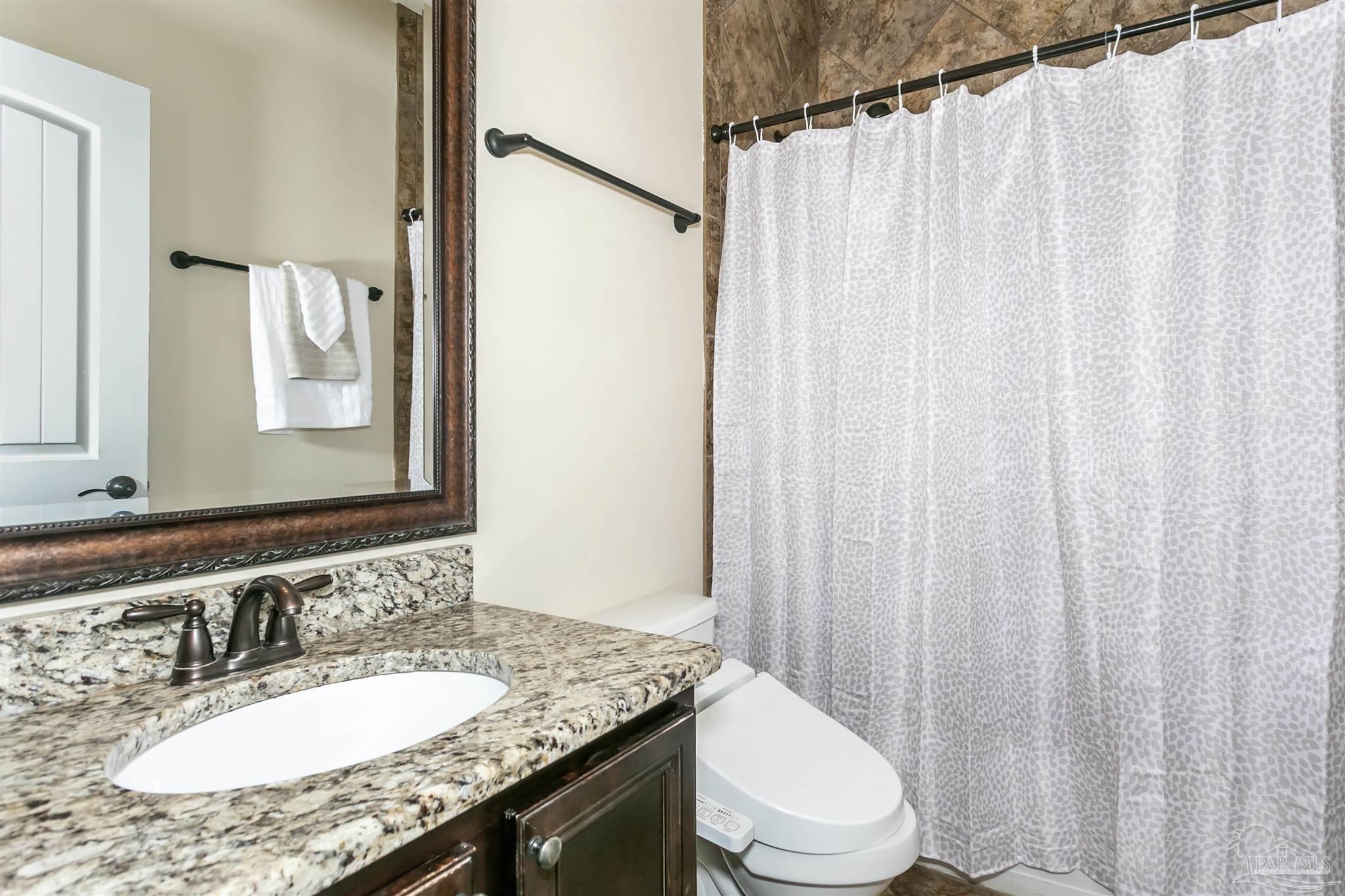 8414 Foxtail Loop Pensacola, FL 32526 - Photo 13 of 22 a bathroom with a granite countertop sink toilet and mirror