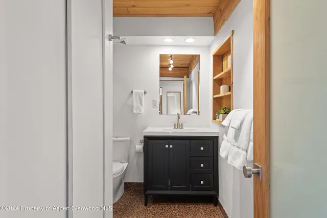 a bathroom with a granite countertop sink a toilet and a mirror