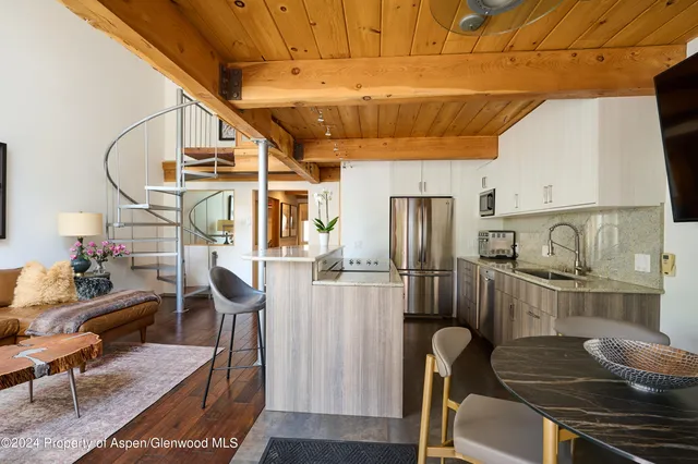 a kitchen with stainless steel appliances kitchen island granite countertop a table chairs and a refrigerator