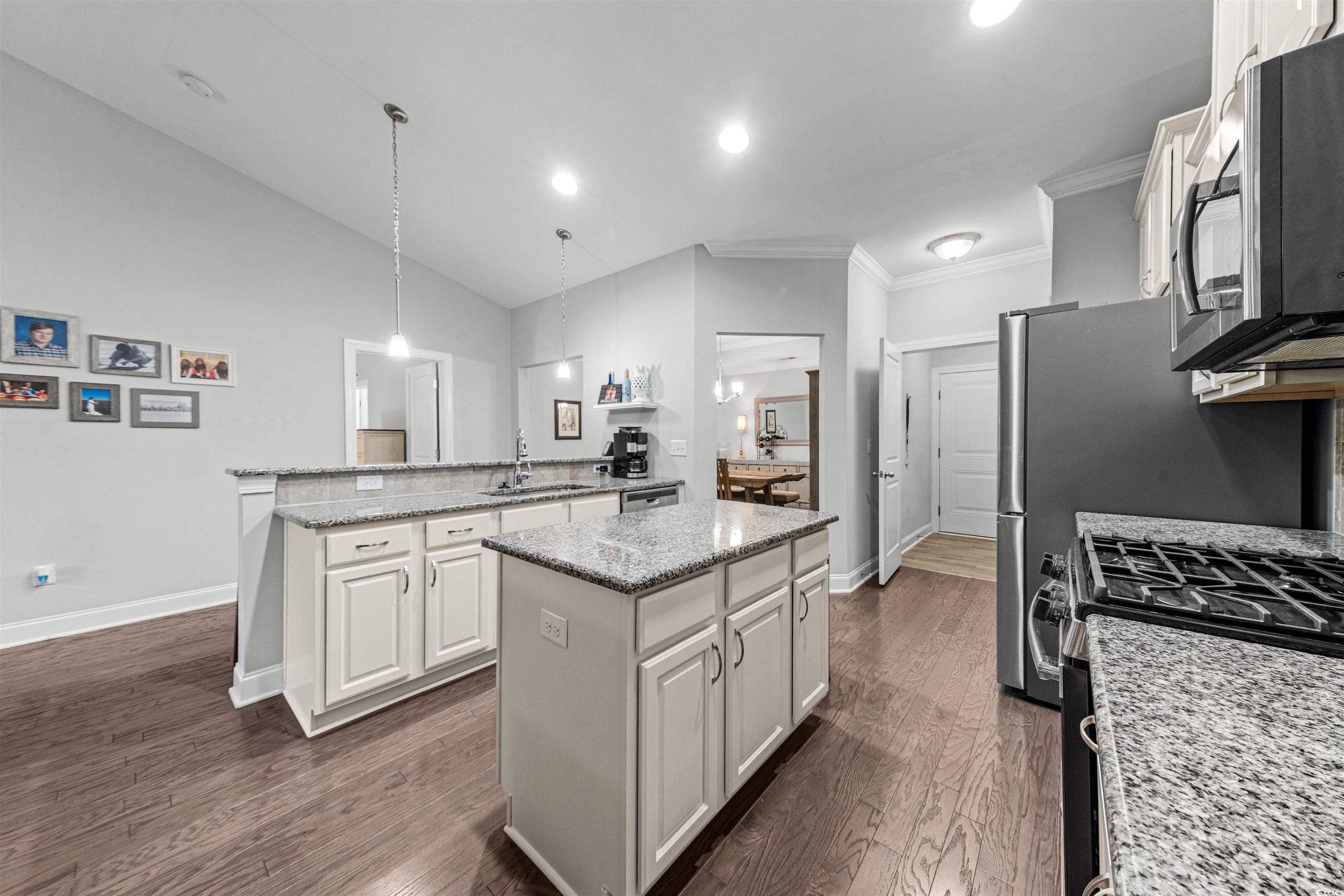 136 Parmelee Drive, Unit C Murrells Inlet, SC 29576 - Photo 14 of 40 Kitchen featuring lofted ceiling, hanging light fixtures, stainless steel appliances, light stone counters, and white cabinets