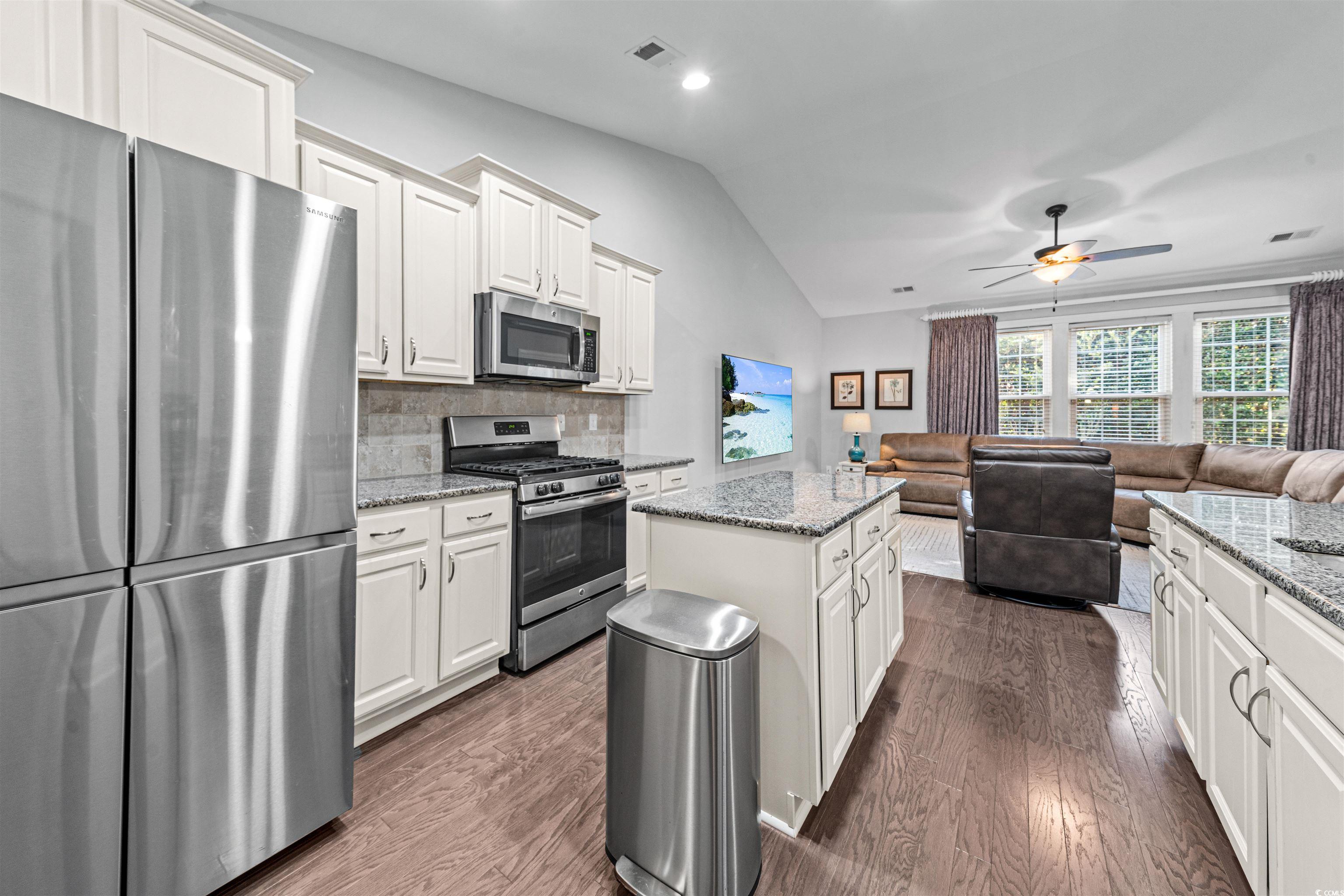 136 Parmelee Drive, Unit C Murrells Inlet, SC 29576 - Photo 17 of 40 Kitchen featuring appliances with stainless steel finishes, a kitchen island, light stone counters, white cabinets, and lofted ceiling
