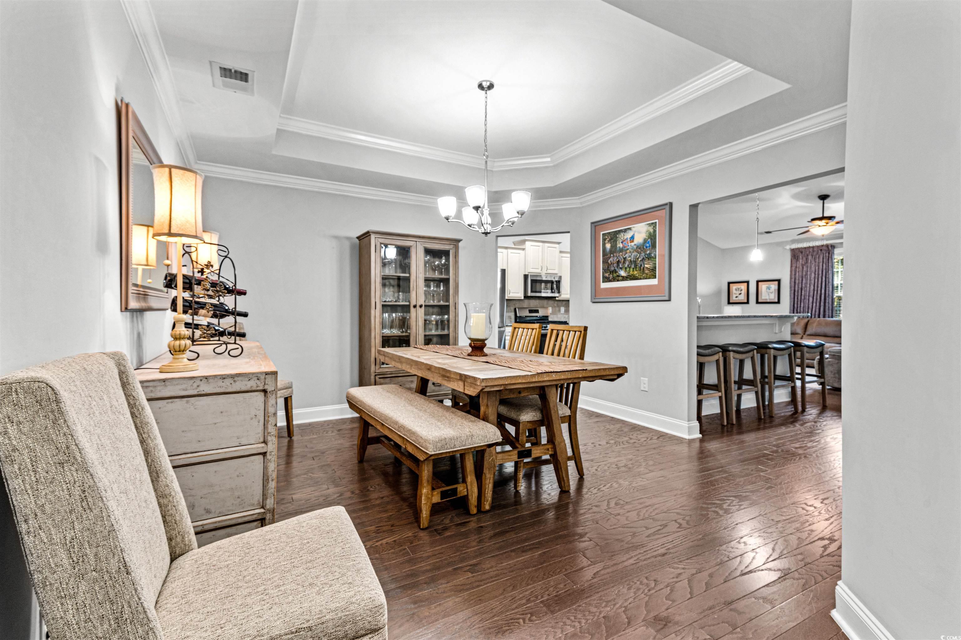 136 Parmelee Drive, Unit C Murrells Inlet, SC 29576 - Photo 7 of 40 Dining space with a tray ceiling, ornamental molding, ceiling fan, dark wood-type flooring, and a chandelier