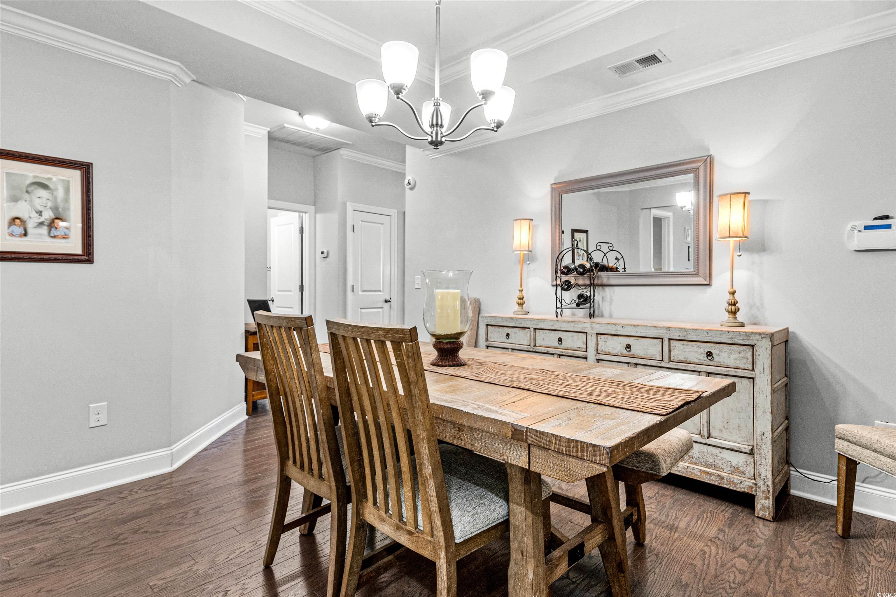 136 Parmelee Drive, Unit C Murrells Inlet, SC 29576 - Photo 9 of 40 Dining area featuring dark wood finished floors, crown molding, and a chandelier