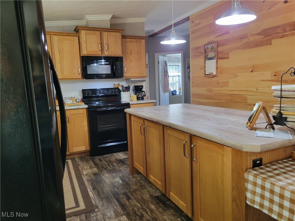 85645 Merryman Road Cadiz, OH 43907 - Photo 6 of 38 Kitchen featuring wooden walls, crown molding, decorative light fixtures, black appliances, and dark hardwood /vinyl planking floors