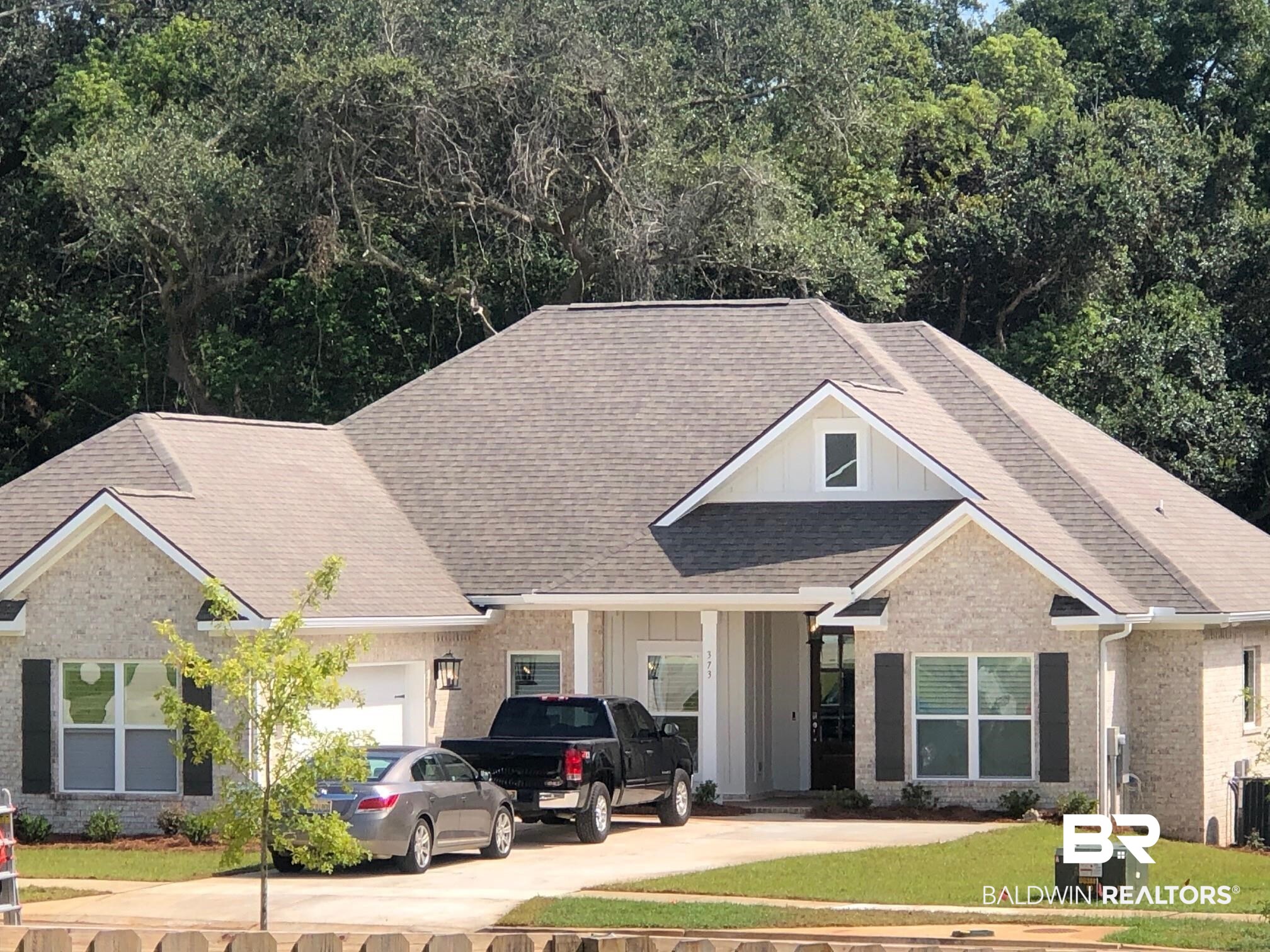 373 Garrison Boulevard Fairhope, AL 36532 - Photo 1 of 35 Craftsman-style house featuring board and batten siding, a garage, a shingled roof, brick siding, and a front lawn