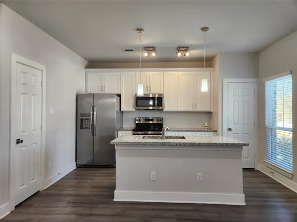 a view of a kitchen with center island wooden floor and staircase