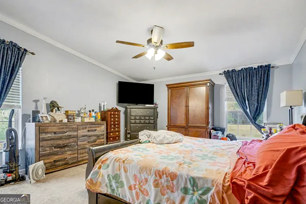 a bedroom with a bed and a flat tv screen on dresser