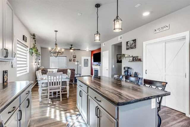 a kitchen with stainless steel appliances kitchen island granite countertop a table chairs in it and wooden floors
