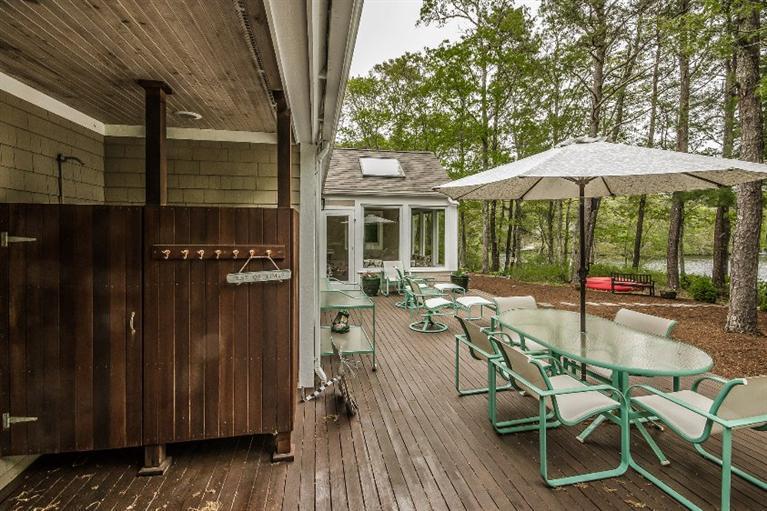 70 Fells Pond Road Mashpee, MA 02649 - Photo 28 of 34 a view of a patio with table and chairs under an umbrella with wooden fence