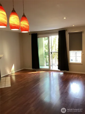 a view of an empty room with wooden floor and windows