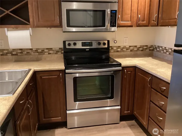 a kitchen with granite countertop a stove top oven microwave and cabinets
