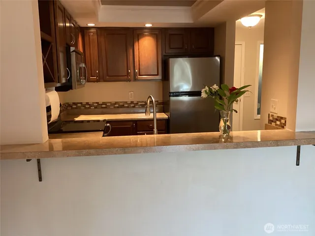 a view of kitchen with stainless steel appliances kitchen island granite countertop a refrigerator and a sink