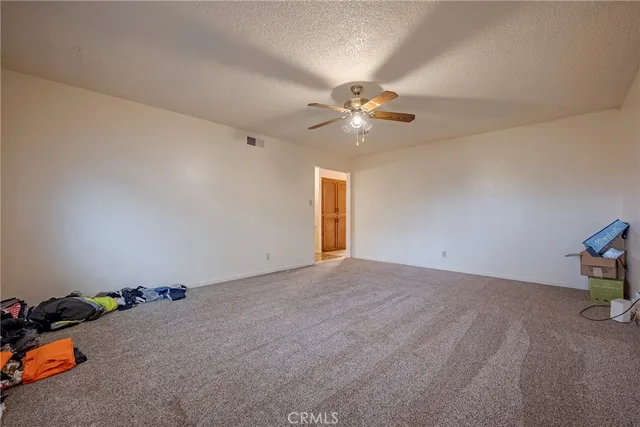 an empty room with a chandelier fan and windows