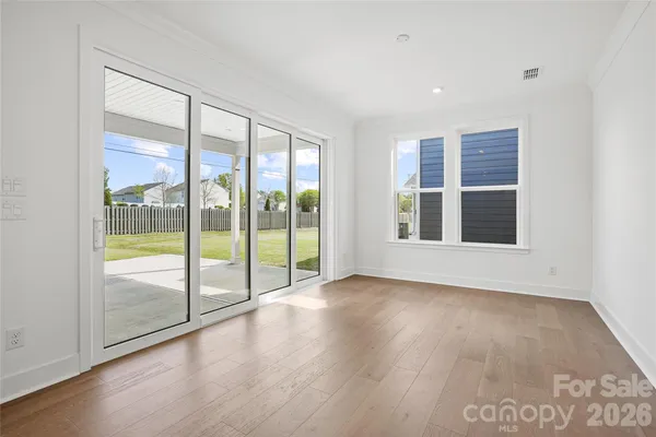 a view of an empty room with wooden floor and doors