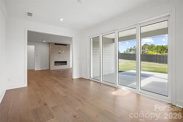 a view of empty room with wooden floor and floor to ceiling window