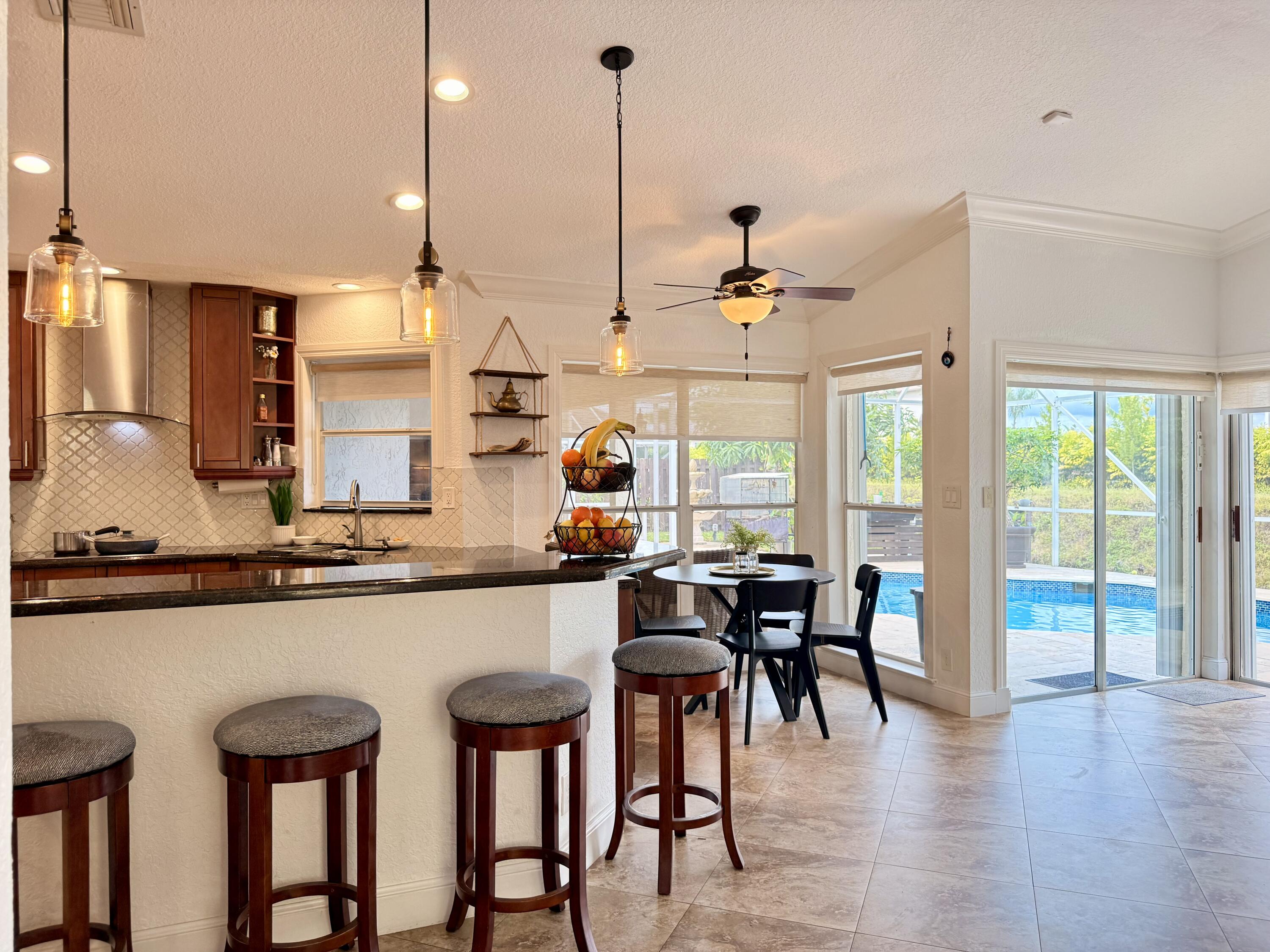 9669 Carousel Circle North Boca Raton, FL 33434 - Photo 3 of 22 a kitchen with stainless steel appliances granite countertop table chairs stove and wooden floor