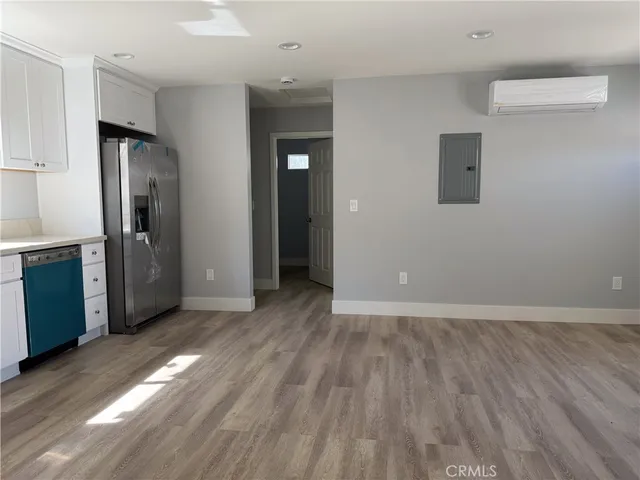 an empty room with wooden floor and a kitchen