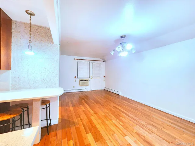 a room with kitchen island a chandelier and wooden floor
