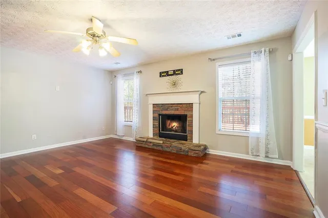 a view of an empty room with wooden floor fireplace and a window