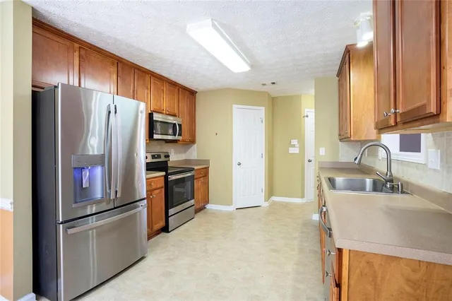 a kitchen with stainless steel appliances granite countertop a refrigerator and a sink