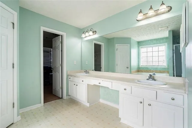 a spacious bathroom with a double vanity sink a mirror and a bathtub