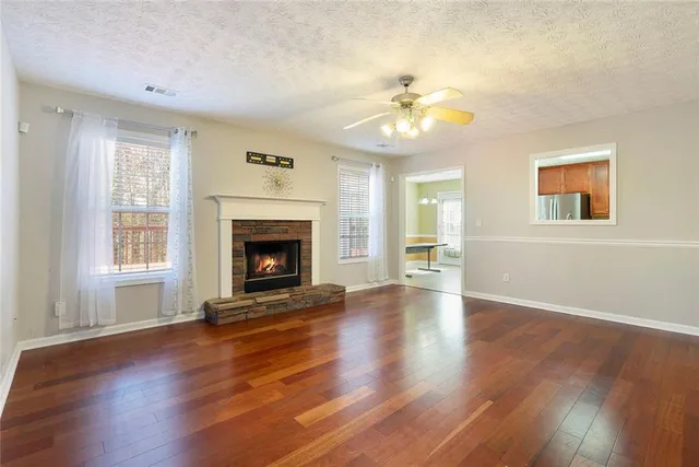 a view of an empty room with wooden floor fireplace and a window